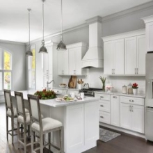 open kitchen with white shaker cabinets, large island, white wood range hood with holiday decorations