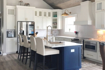 This kitchen redesign uses a vaulted ceiling, glass-front cabinets and a blue island to make dramatic statements in this bright space