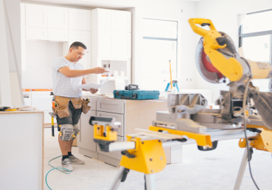 White shaker kitchen cabinets being installed by contractor surrounded by power tools