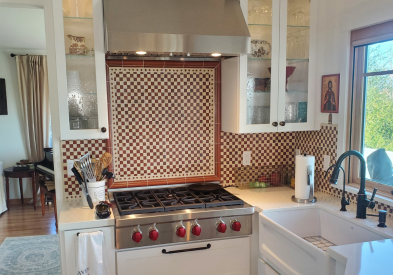 White shaker kitchen cabinets with a large white farm sink and Italian-style tile backsplash