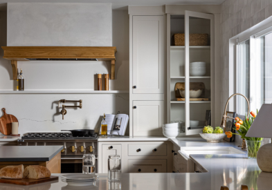 Light cream kitchen cabinets in inset door style with medium wood accents and a plaster kitchen hood