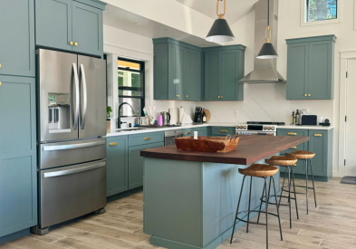 Turquoise shaker kitchen design with gold hardware, dark butcher block countertops and light flooring