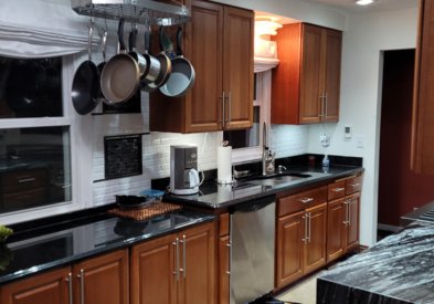 Raised panel cherry kitchen cabinets with black granite countertops and a waterfall edge