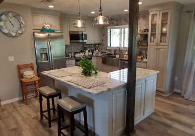 Light cream raised panel kitchen design with modern glass pendant lights and L-shaped island