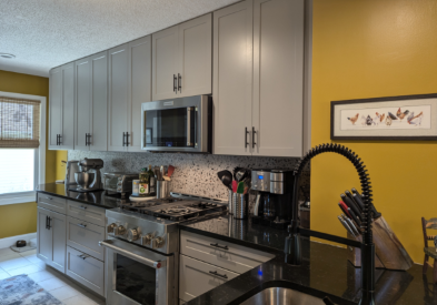 Gray shaker kitchen cabinets with black cabinet hardware and yellow walls