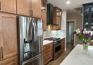 Light wood kitchen cabinets with indigo furniture-style accents and white quartz countertops