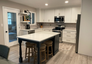 White shaker kitchen design with a dark indigo-blue island with furniture legs and seating