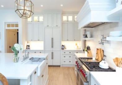 Large white shaker inset kitchen remodel with stacked glass cabinets, a matching kitchen hood, built-in appliances, and a large white kitchen island