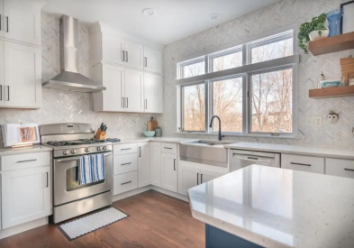 White shaker stacked cabinets with a navy blue kitchen island and white quartz countertops