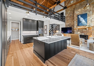 Black shaker kitchen cabinets with a white stone countertop and rustic beams above