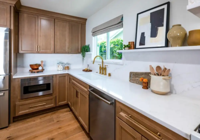 Medium-toned wood cabinets with gold hardware, white countertops, and floating shelves