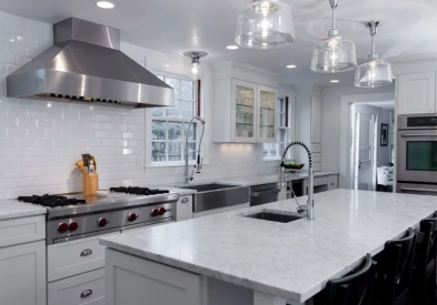 White shaker kitchen cabinets with large stainless range hood and island