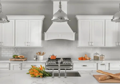 White shaker kitchen cabinets with wood hood and polished chrome pendants