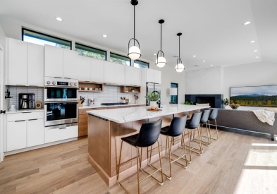 Mid-Century Modern white and light wood kitchen with large island and spherical pendants with black metal accents