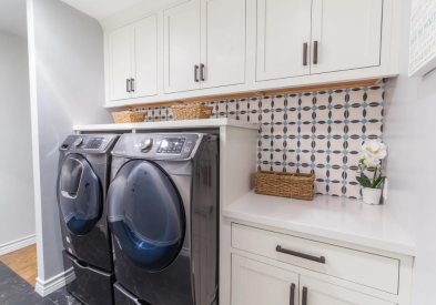 White inset shaker laundry room wall cabinets with a front load gray washer and dryer with countertop across the top