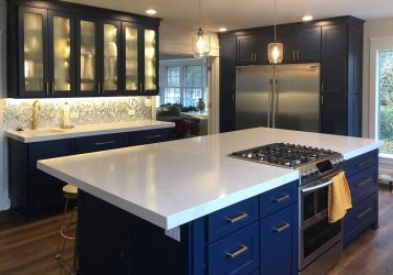 Large island with navy cabinets and white countertop facing pantry cabinets and second sink