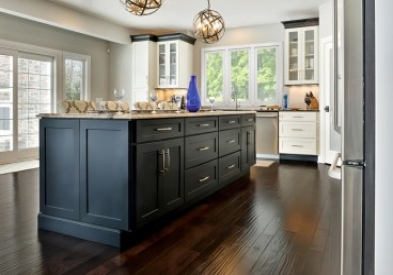 Beautifully designed open floor plan kitchen features painted shaker style cabinetry by CliqStudios. Shown Dayton shaker cabinet style in painted White finish and paired with Dayton in painted Carbon finish.