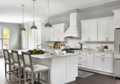 open kitchen with white shaker cabinets, large island, white wood range hood with holiday decorations