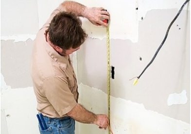 contractor measuring wallboard in kitchen remodel