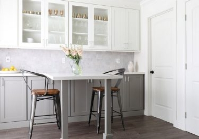 White and gray shaker kitchen cabinets with small, eat-in space with white quartz countertops integrated