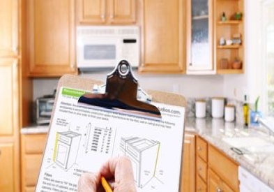 Golden oak kitchen in the background with homeowner holding clipboard planning their kitchen remodel