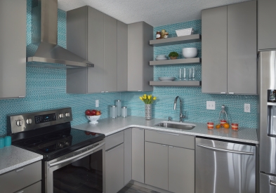 Light gray slab door modern kitchen design with turquoise tile backsplash and white countertops