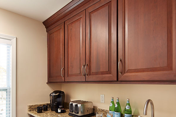 Cherry kitchen wall cabinets with raised panel design and decorative crown molding