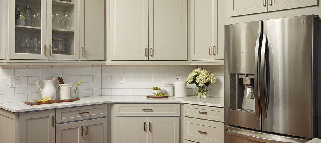 Light gray shaker cabinets with gold hardware and some glass doors for display. Wall and base cabinet types