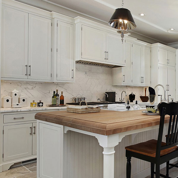 Cli1Studios Painted White inset cabinets featuring butcher block countertop, under cabinet mount range hood, beadboard island and decorative island leg