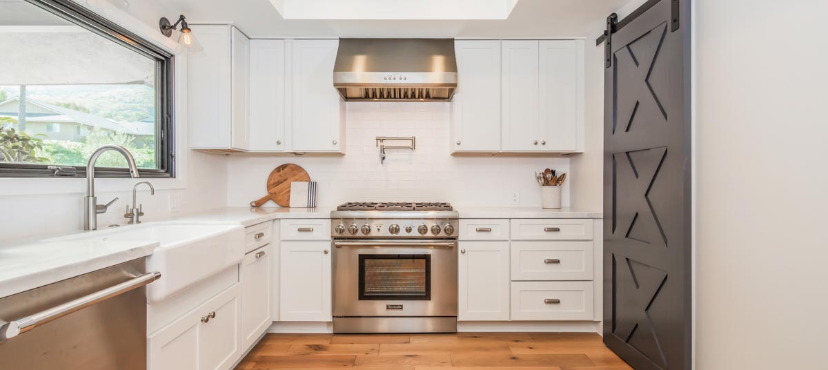 white shaker style cabinetry with subway tile backsplash and gray barn door