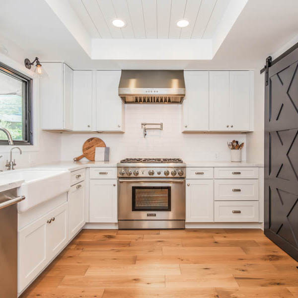 White kitchen with shaker cabinets barn door and stainless appliances