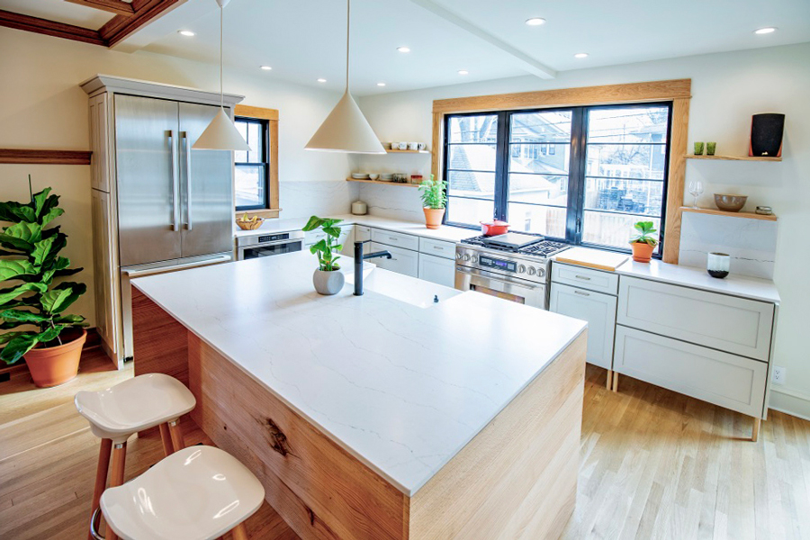 Modern kitchen design featuring white marble countertops, light gray kitchen cabinets, and brass hardware