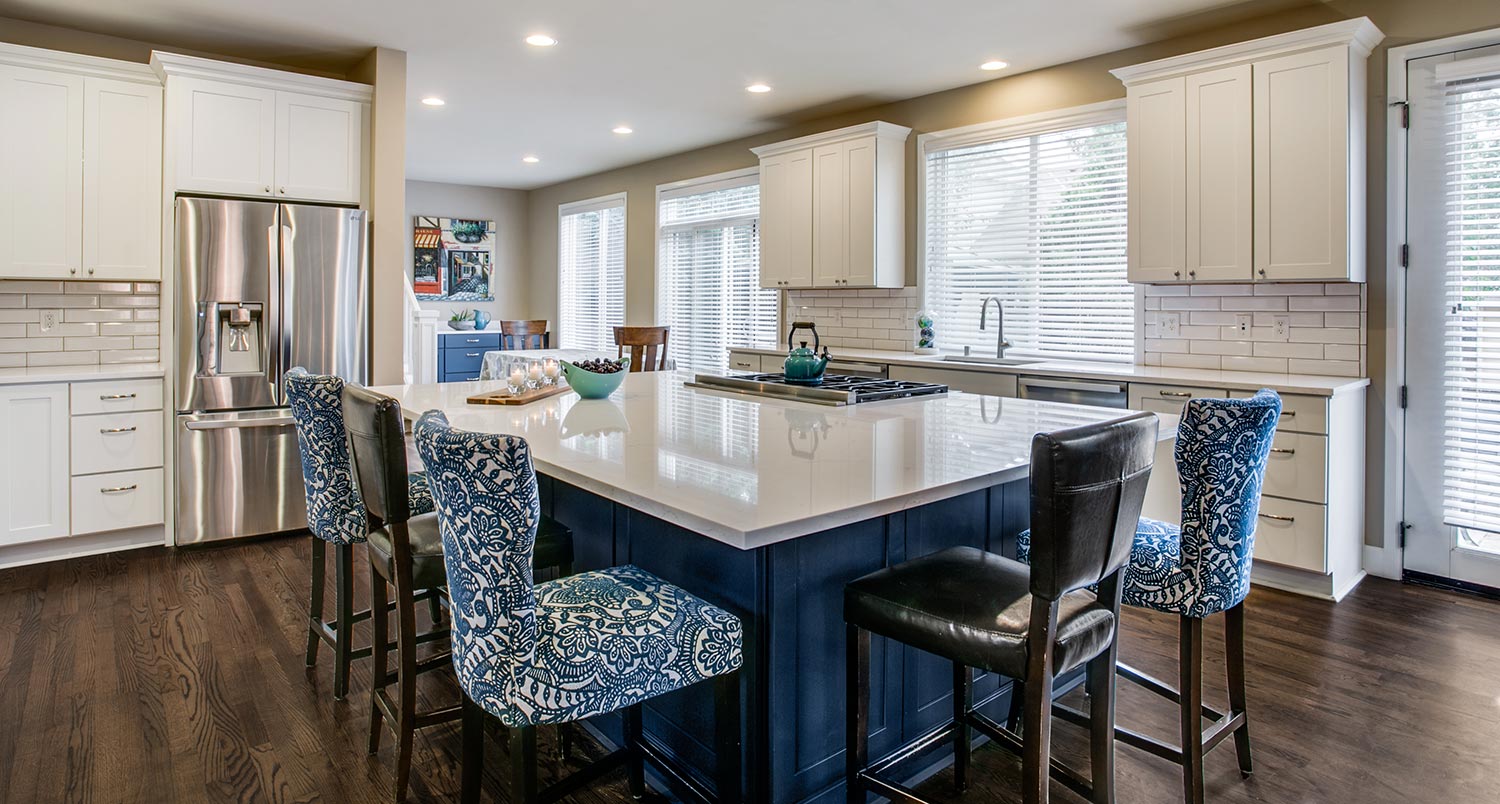 large blue island surrounded by blue chairs and installed white kitchen cabinets