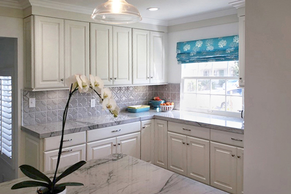 Corner of kitchen with white Decorative cabinets, gray tile backsplash and a window