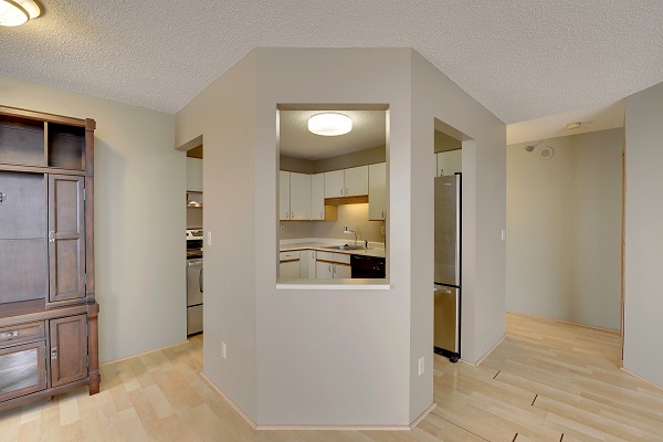 an empty condo with a kitchen with a peek-a-boo window to the living area.