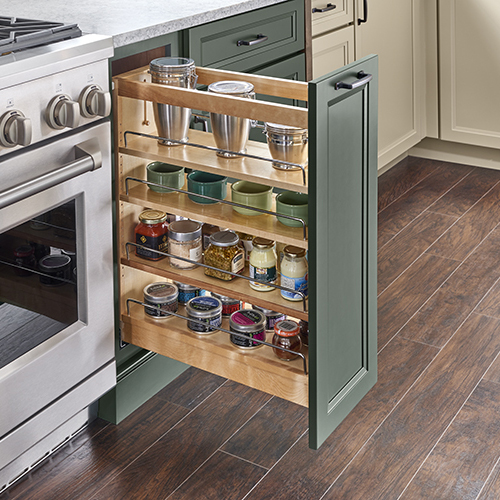 Pull-out spice cabinet with multiple adjustable shelves next to range appliance with painted green cabinet door