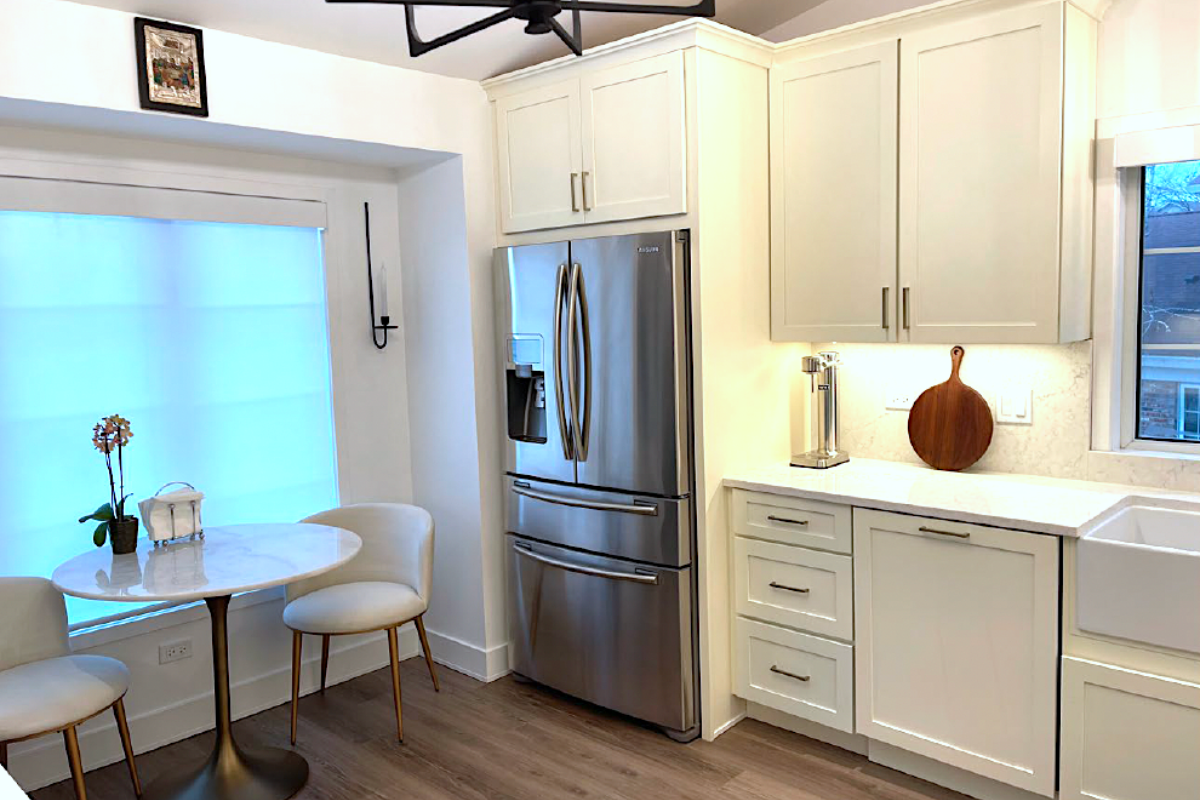 CliqStudios project: cream-colored shaker kitchen cabinets with a stainless steel french door refrigerator and small eat-in marble kitchen table