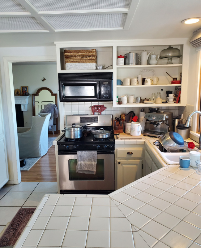 Before photo with old white cabinets, white square tile countertops and a grid ceiling