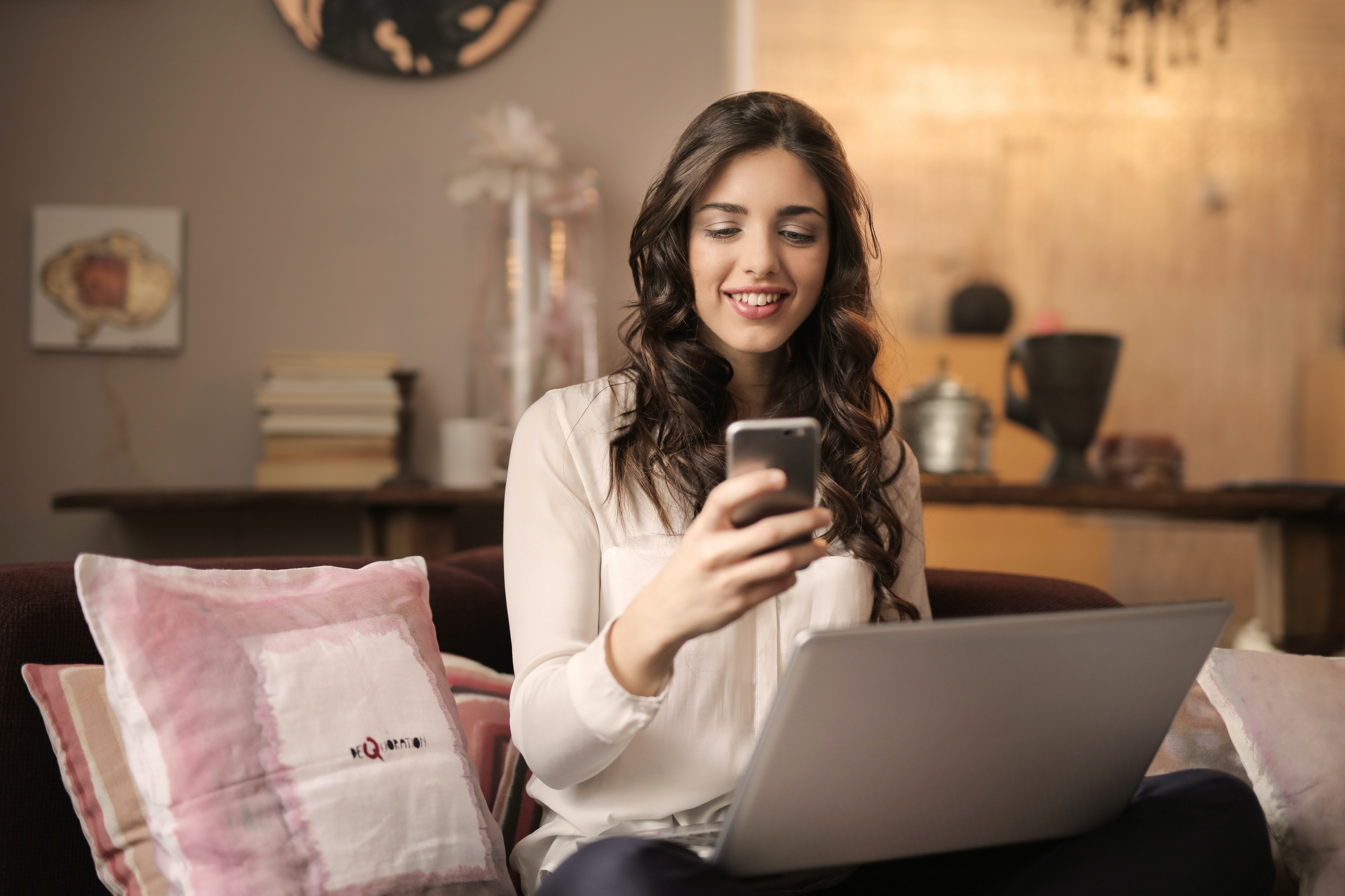 Woman searching the internet on her phone and laptop Woman searching the internet on her phone and laptop