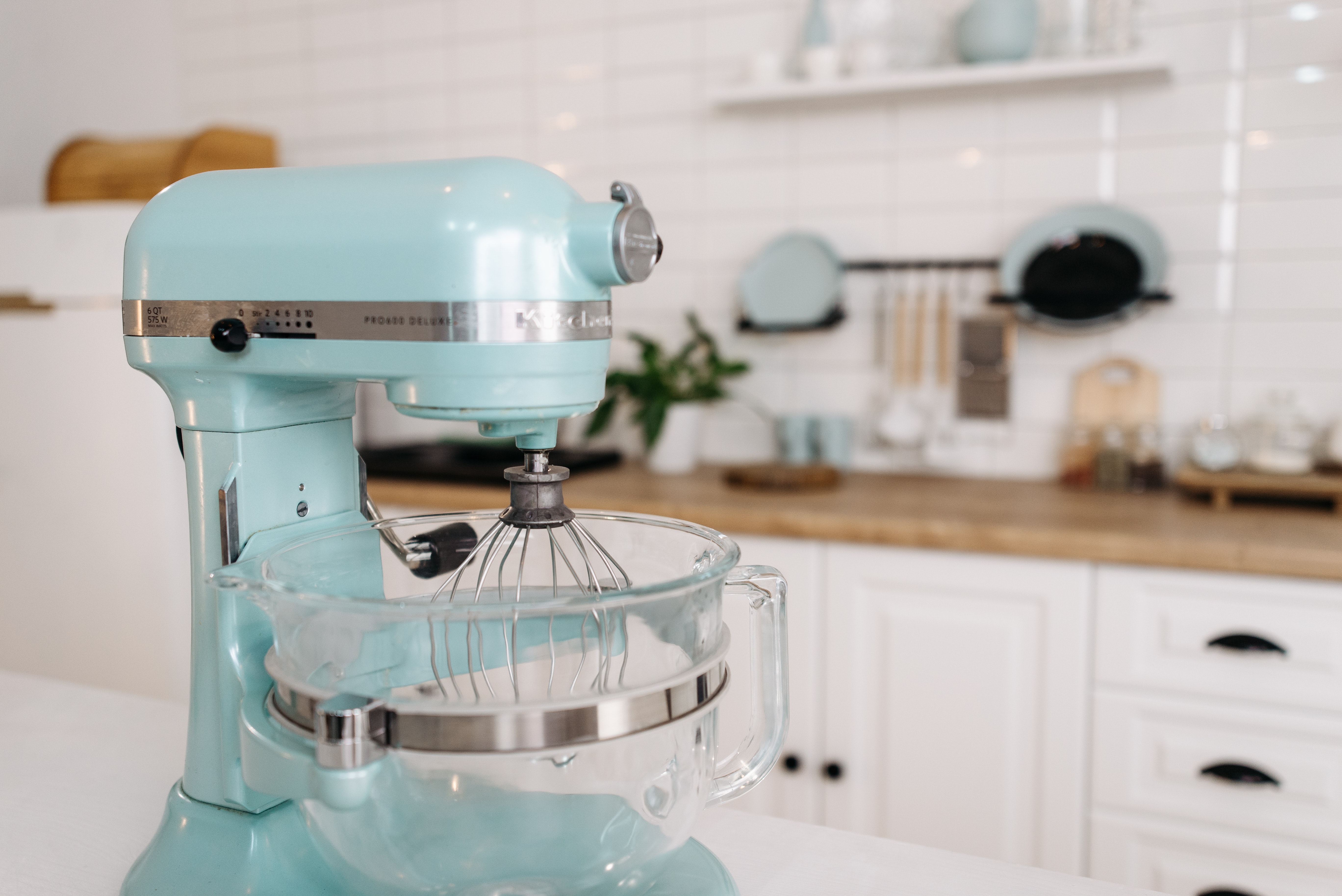 Aqua blue KitchenAid stand mixer sitting on decorative white kitchen cabinets