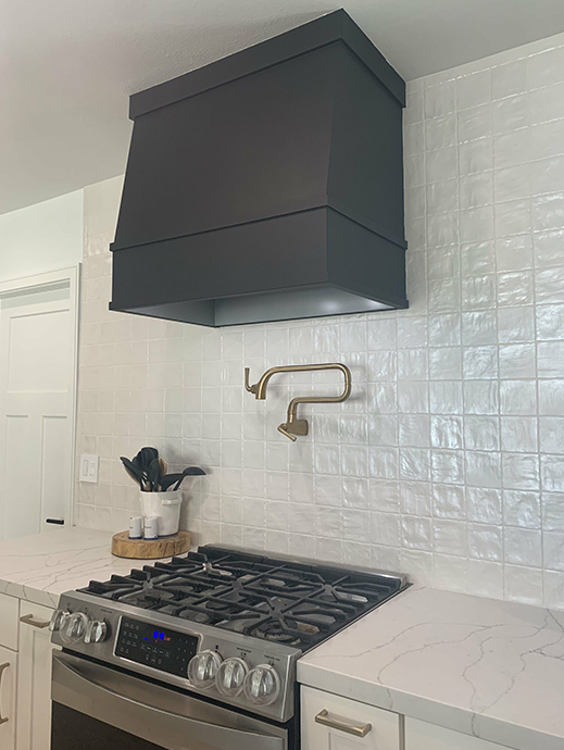 White kitchen cabinets with angled wood kitchen hood in black finish