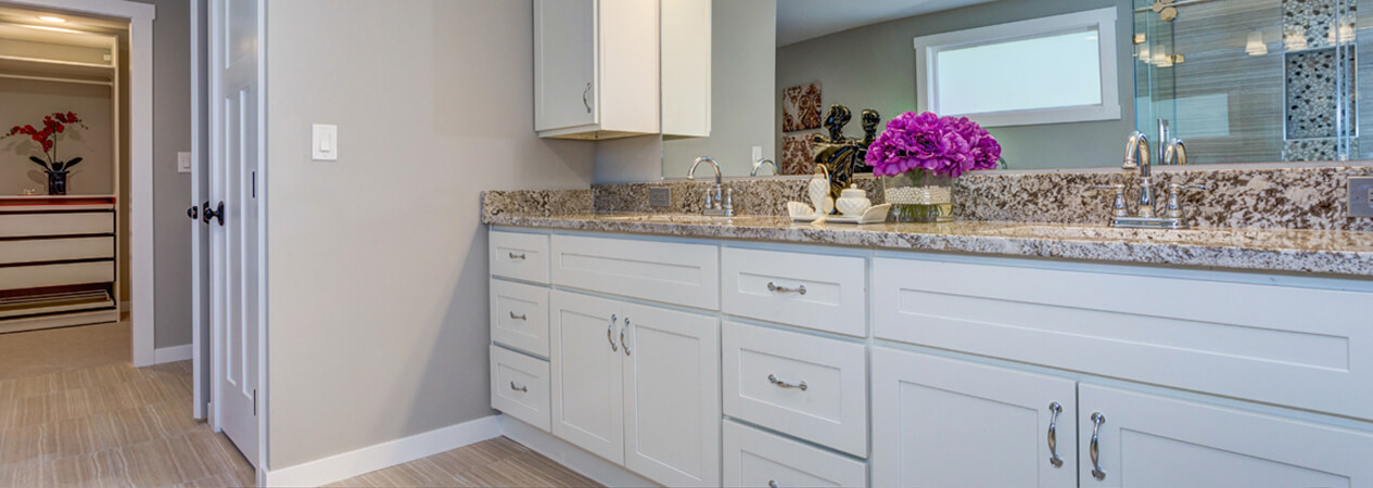 Long white shaker vanity cabinet with granite countertops