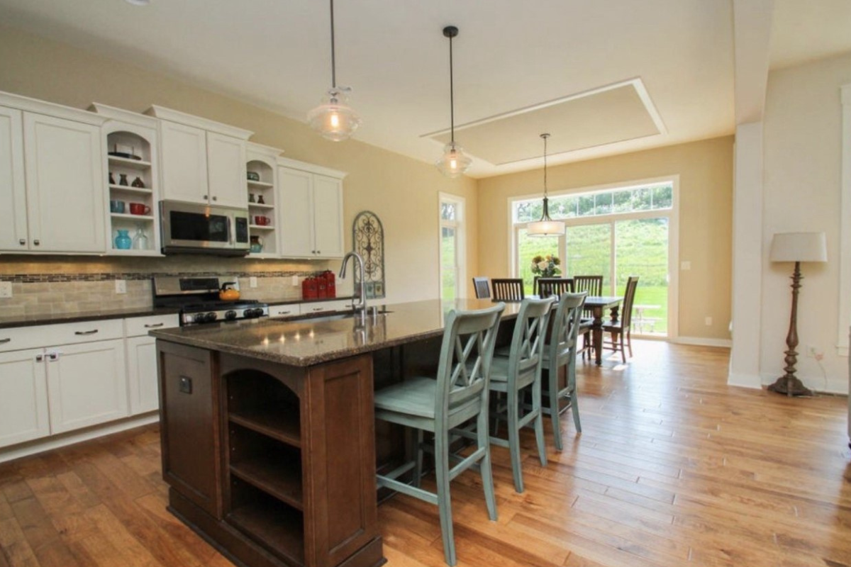 Transitional white shaker kitchen with a cherry shaker island, and blue farmhouse-style chairs for seating