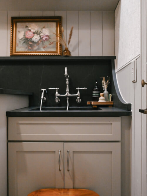 Laundry room wall with beige laundry room sink cabinet, brushed nickel hardware and black quartz countertops