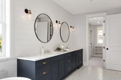 Black inset bathroom vanity with gold hardware and white countertops