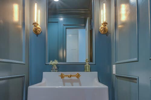 Bright blue paneled powder room with porcelain sink