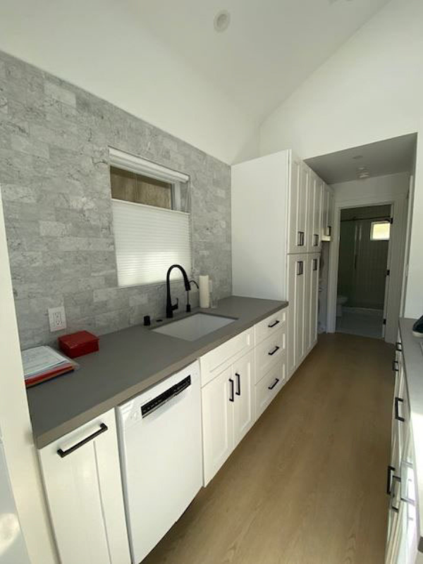 Contemporary white shaker kitchen and island with black cabinet hardware and built-in stackable washer and dryer.