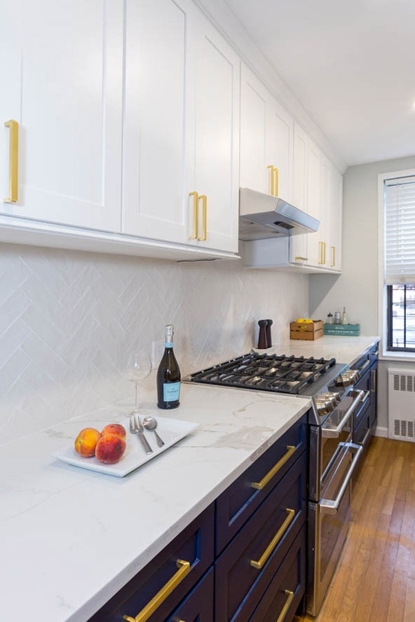 blue and white cabinets with brass bar hardware and white pearlescent, herringbone backsplash