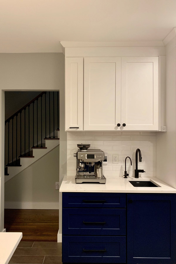 open kitchen with l-shaped peninsula, blue base cabinets and white upper cabinets