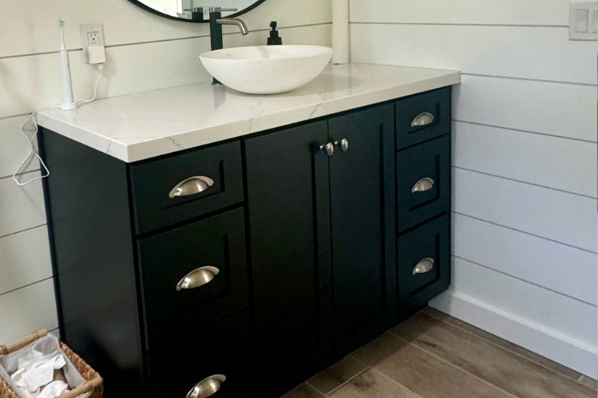 Black shaker vanity cabinet with drawers on either side and a sink in the center